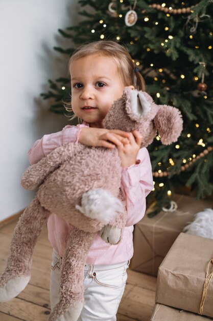 Un enfant heureux a reçu un lapin en peluche de cadeau de Noël