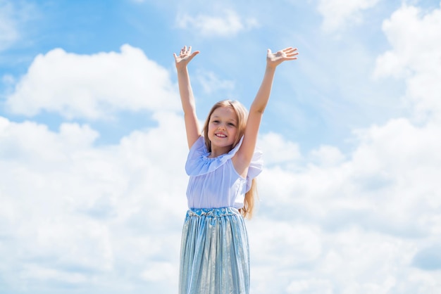 Enfant heureux en robe d'été sur fond de ciel insouciant