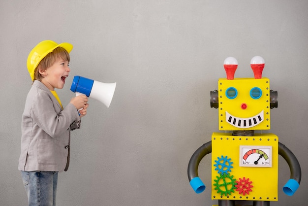 Enfant heureux avec robot. Enfant drôle jouant à la maison. Garçon criant par haut-parleur. Concept de technologie de réussite, de créativité et d'innovation