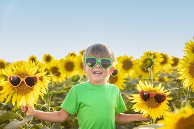 Enfant heureux s'amusant dans le champ printanier de tournesols. Outdoor portrait of kid contre fond de ciel bleu