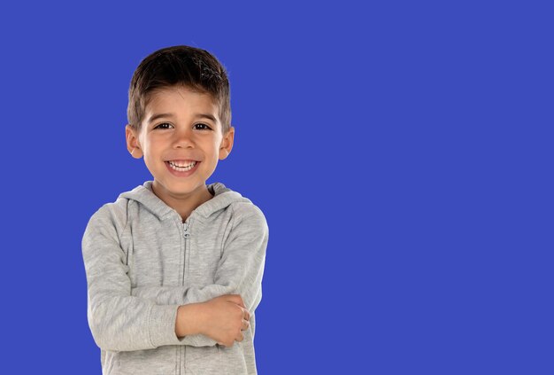 Enfant heureux avec ses bras croisés isolé sur un fond bleu