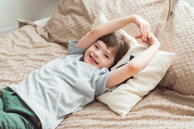 Enfant heureux avec le syndrome de Down allongé sur le lit