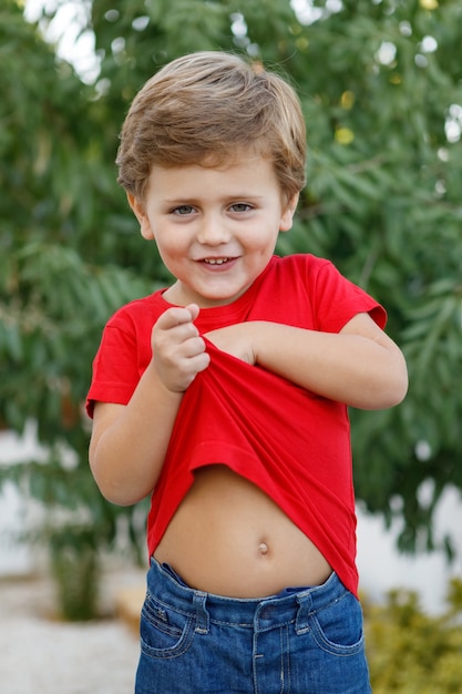 Enfant heureux avec un t-shirt rouge dans le jardin