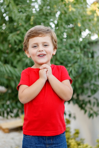 Enfant heureux avec un t-shirt rouge dans le jardin