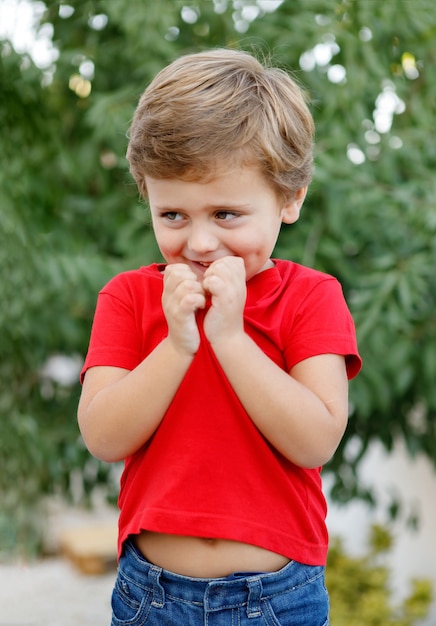 Enfant Heureux Avec Un T-shirt Rouge Dans Le Jardin