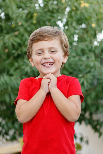 Enfant heureux avec un t-shirt rouge dans le jardin