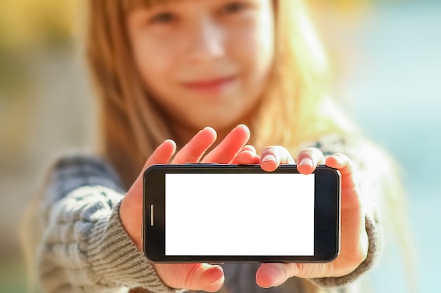 Un enfant heureux avec téléphone prenant selfie dans la nature dans le parc voyage