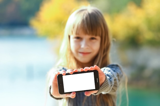 Un enfant heureux avec téléphone prenant selfie dans la nature dans le voyage du parc