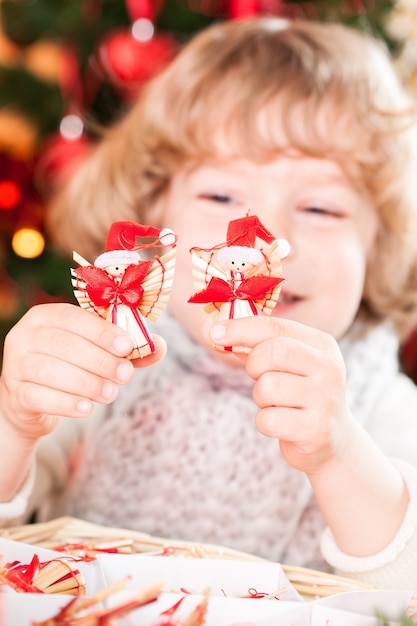 Enfant heureux tenant des décorations écologiques faites à la main contre les lumières de Noël