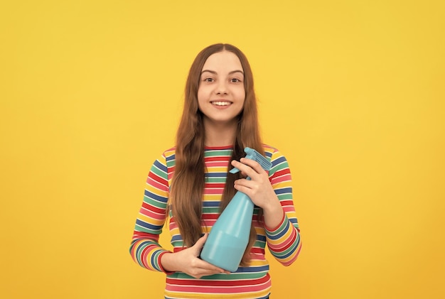 Un enfant heureux tient un produit de pulvérisation désinfectant dans une bouteille pour la désinfection de fond jaune de l'espace de copie