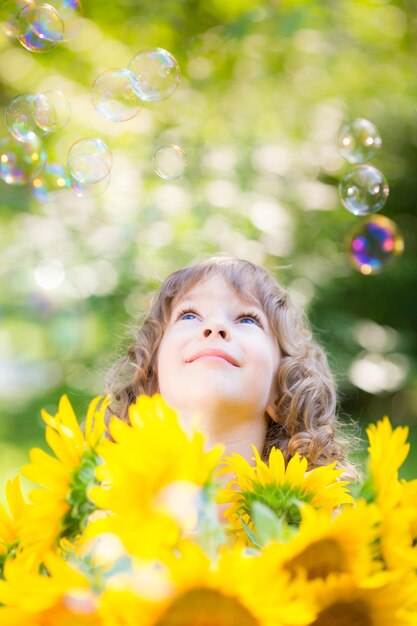 Enfant heureux avec des tournesols à l'extérieur dans le parc du printemps