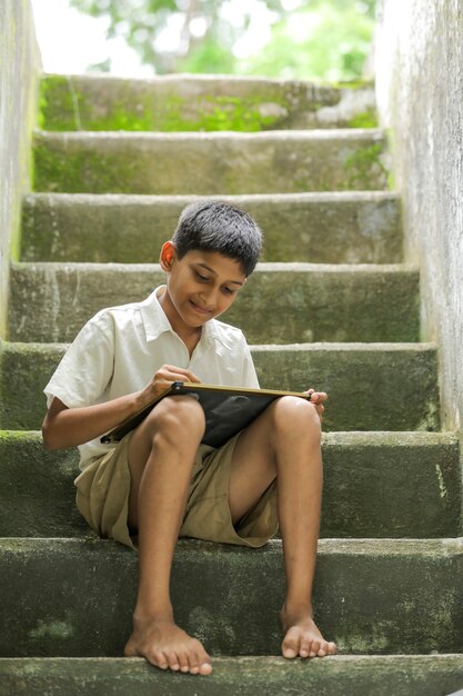 Enfant indien écrit l'alphabet ABCD sur tableau noir