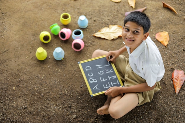 Enfant indien écrit l'alphabet ABCD sur tableau noir