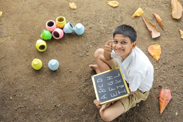 Enfant indien écrit l'alphabet ABCD sur tableau noir