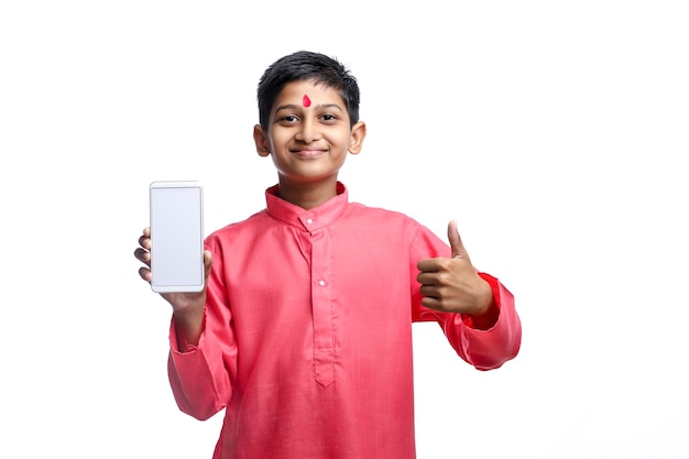 Enfant indien en tenue traditionnelle et montrant l'écran du smartphone sur fond blanc.