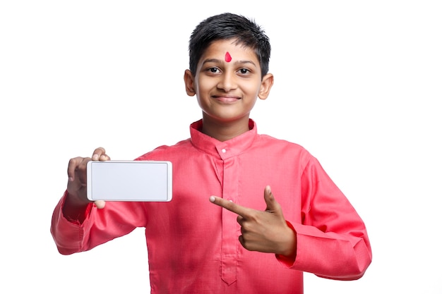 Enfant indien en tenue traditionnelle et montrant l'écran du smartphone sur fond blanc.