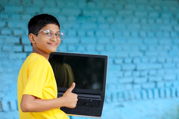Enfant indien utilisant un ordinateur portable à la maison. assister à des cours en ligne