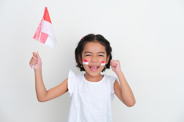Enfant indonésien acclamant et poing fermé en tenant le drapeau du pays