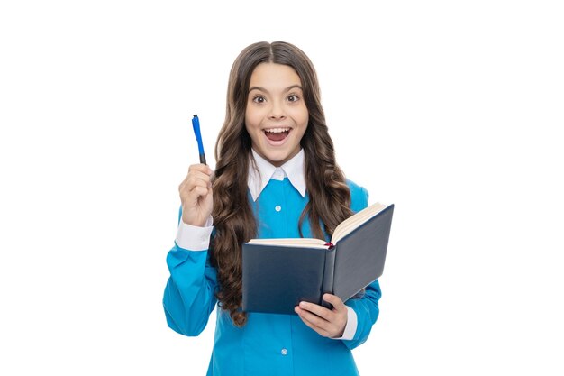 Un enfant inspiré tient un livre scolaire en gardant un stylo soulevé isolé sur blanc, inspiration.