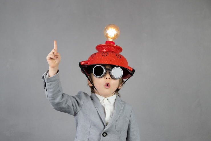 Photo un enfant intelligent prétend être un homme d'affaires. enfant drôle portant un casque avec ampoule. concept d'éducation, d'intelligence artificielle et d'idée d'entreprise