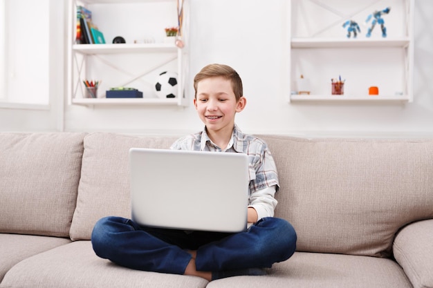 Enfant et internet, garçon heureux avec ordinateur portable à la maison