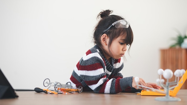 Enfant inventif construisant des voitures de robot à la maison