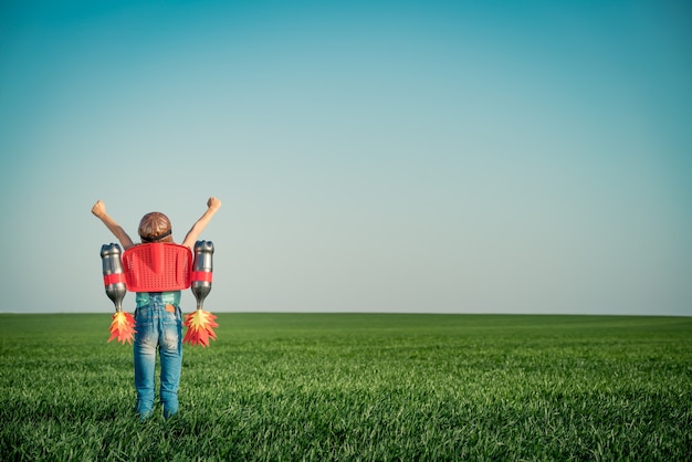 enfant avec jet pack enfant en plein air jouant dans un champ de printemps vert