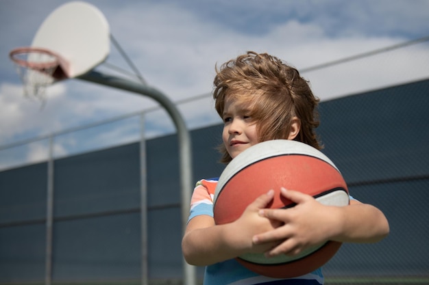 Enfant jouant au basket-ball petit enfant de sport caucasien jouant au basket-ball tenant un ballon avec un visage heureux un ...