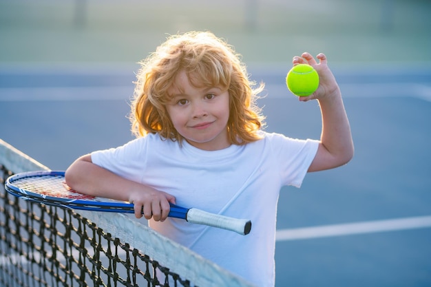 Enfant jouant au tennis sur un court extérieur petit enfant joueur de tennis sur un court portrait de visage d'enfant avec t