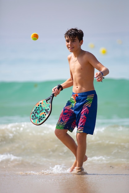 enfant jouant au tennis de plage par une journée ensoleillée