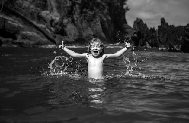 Enfant jouant dans l'eau de l'océan enfant sautant dans les vagues de la mer enfants vacances sur la plage petit garçon excité