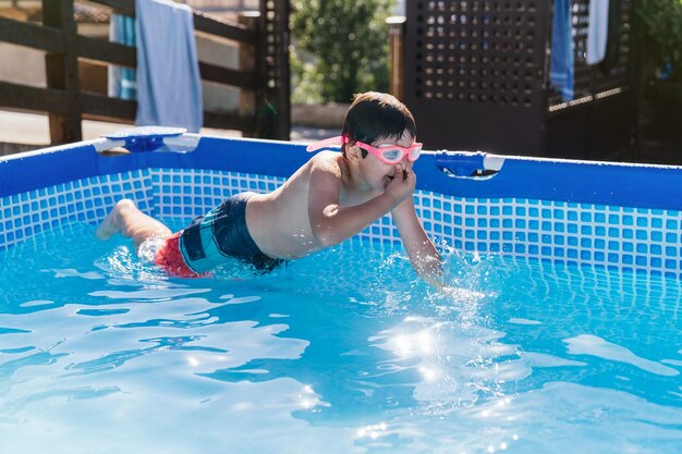 Enfant jouant dans une petite plongée amovible dans l'eau avec ses mains couvrant son nez avec des lunettes