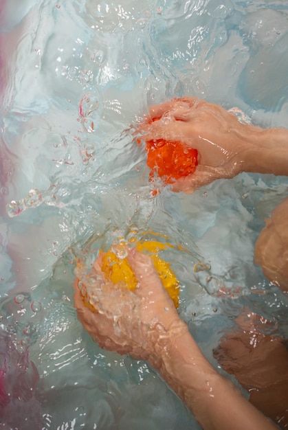 Un enfant jouant avec de l'eau et une balle en caoutchouc en main