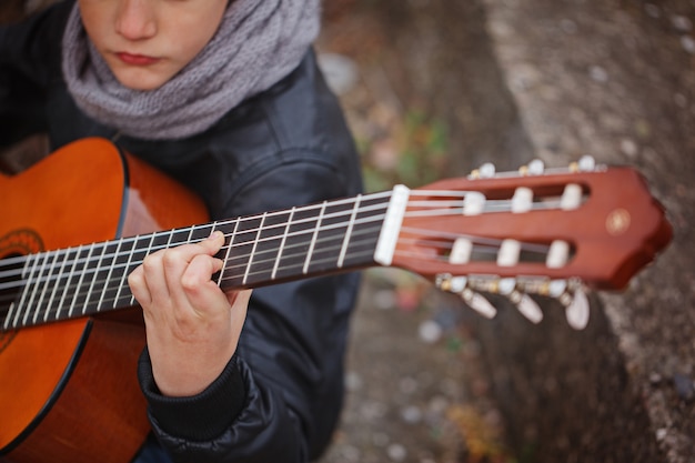 Enfant jouant à la guitare acoustique en gros plan.