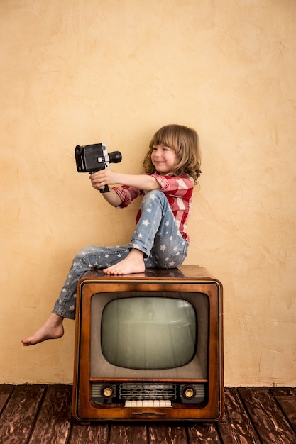 Enfant jouant à la maison. Enfant prenant selfie avec appareil photo rétro. Concept de cinéma