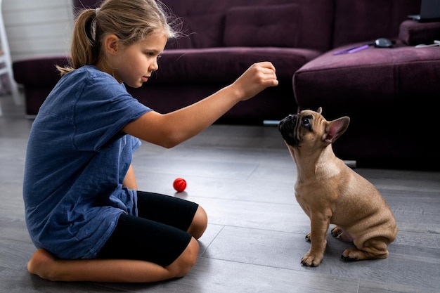 Enfant jouant avec un petit chien fille assise avec un chiot bouledogue français
