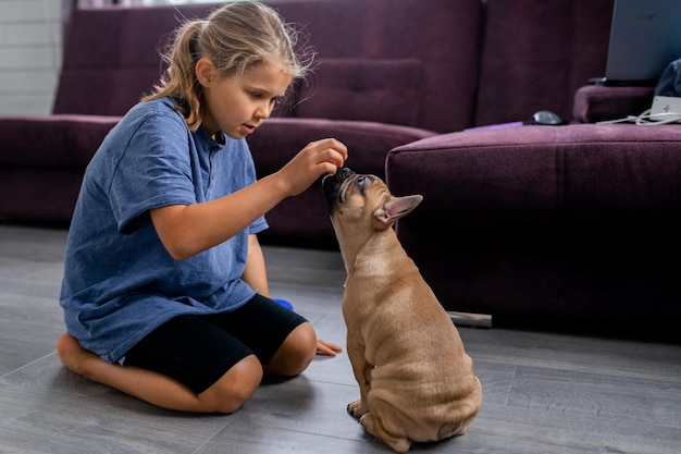 Enfant jouant avec un petit chien fille assise avec un chiot bouledogue français