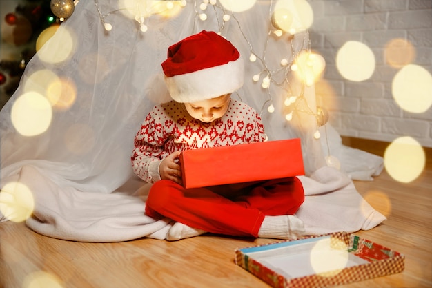 Enfant jouant près de la famille de l'arbre de Noël avec des cadeaux la veille de Noël