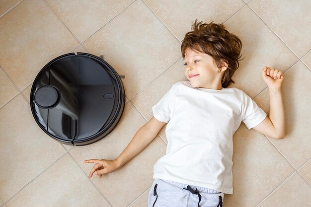 Enfant jouant avec un robot aspirateur sur le sol