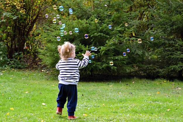 Un enfant joue avec des bulles dans un parc.