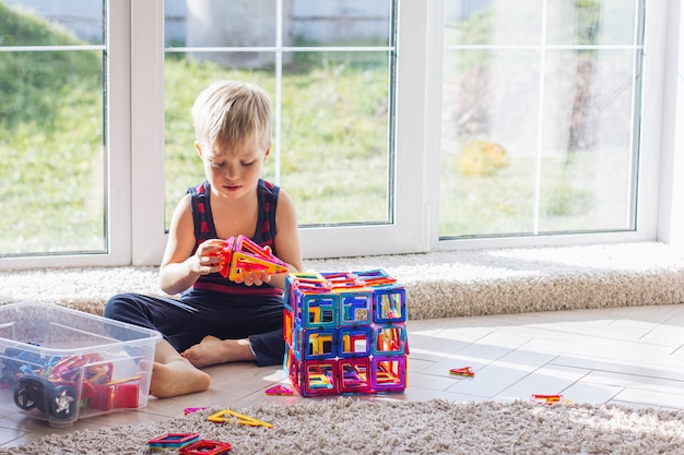 L'enfant joue avec un constructeur magnétique multicolore, construisant une tour. Jouets éducatifs. Un bloc de construction pour un bébé ou un enfant en bas âge Encombrement dans la salle de jeux