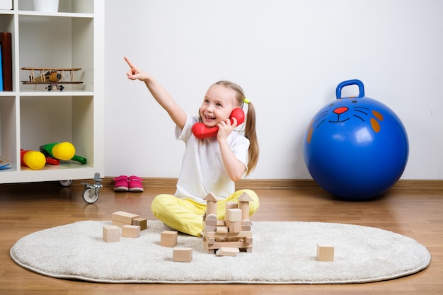 l'enfant joue des cubes sur le tapis et parle au téléphone