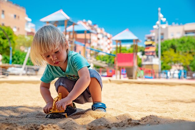 L'enfant joue dans le bac à sable avec une excavatrice