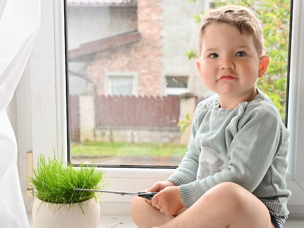 Un enfant joue dans le jardinier sur le rebord de la fenêtre