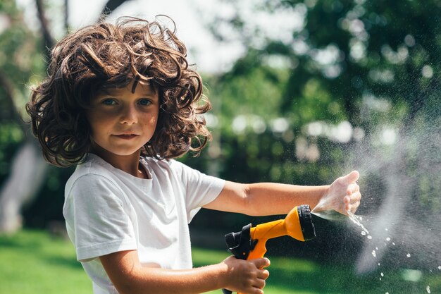 L'enfant joue avec de l'eau dans la cour dans le jardin