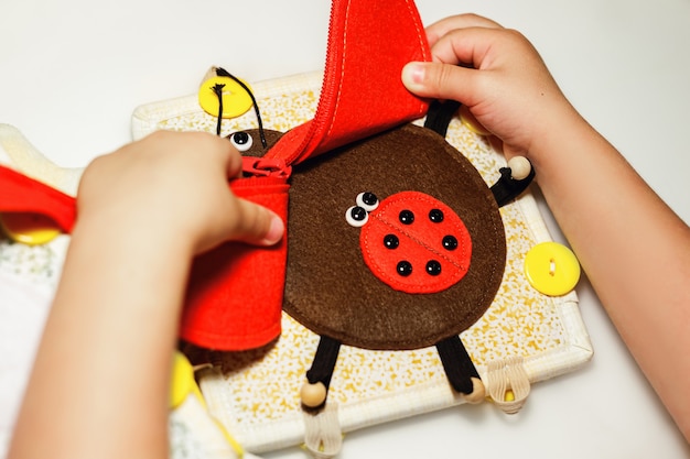 Un enfant joue avec un jouet éducatif coccinelle rouge en feutre concept montessori éducation précoce