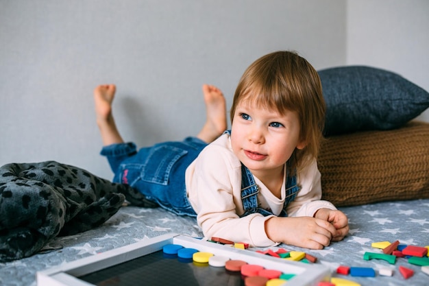 L'enfant joue à la maison un jeu éducatif avec un puzzle magnétique multicolore