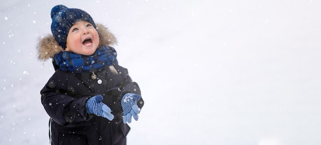 Un enfant joue avec la neige en hiver, aime les flocons de neige, les chutes de neige