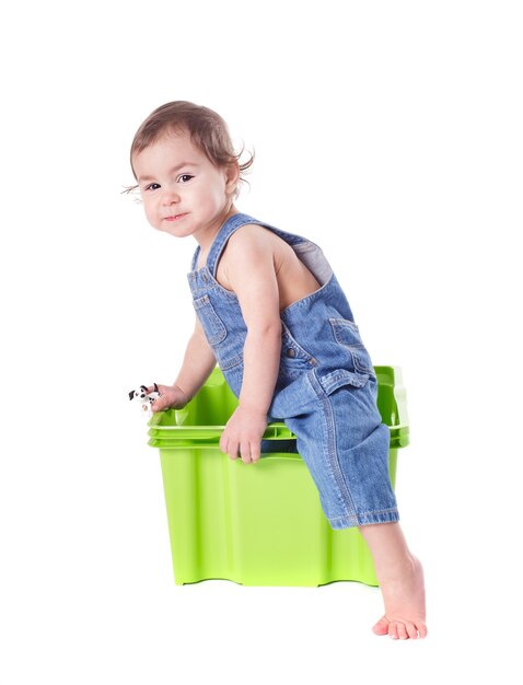 L'enfant joue avec le récipient en plastique d'isolement sur le blanc