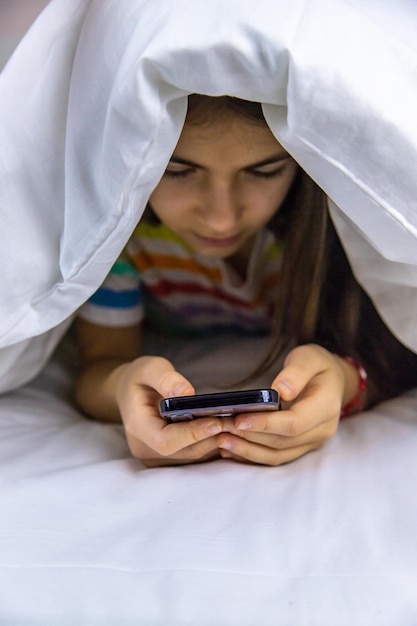 L'enfant joue avec le téléphone au lit Mise au point sélective